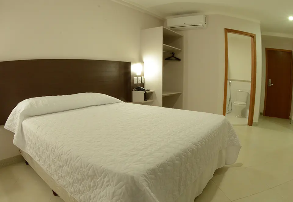 Apartamento com cama de casal, armário aberto e porta do banheiro